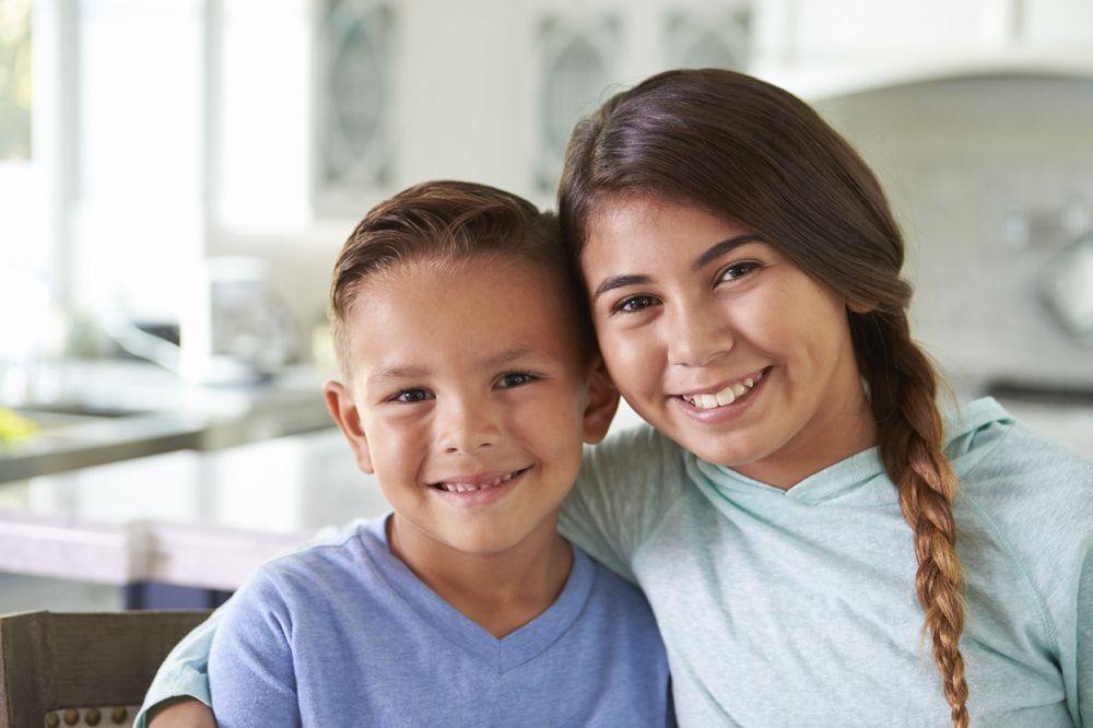 Two young siblings smile at a dentist office 